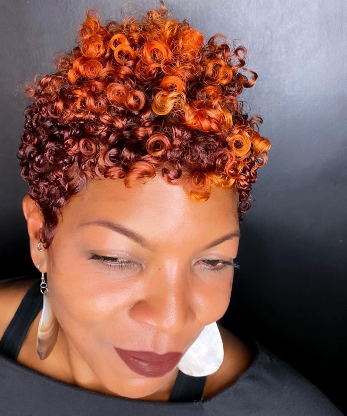 Woman showcasing voluminous copper and auburn curly hairstyle