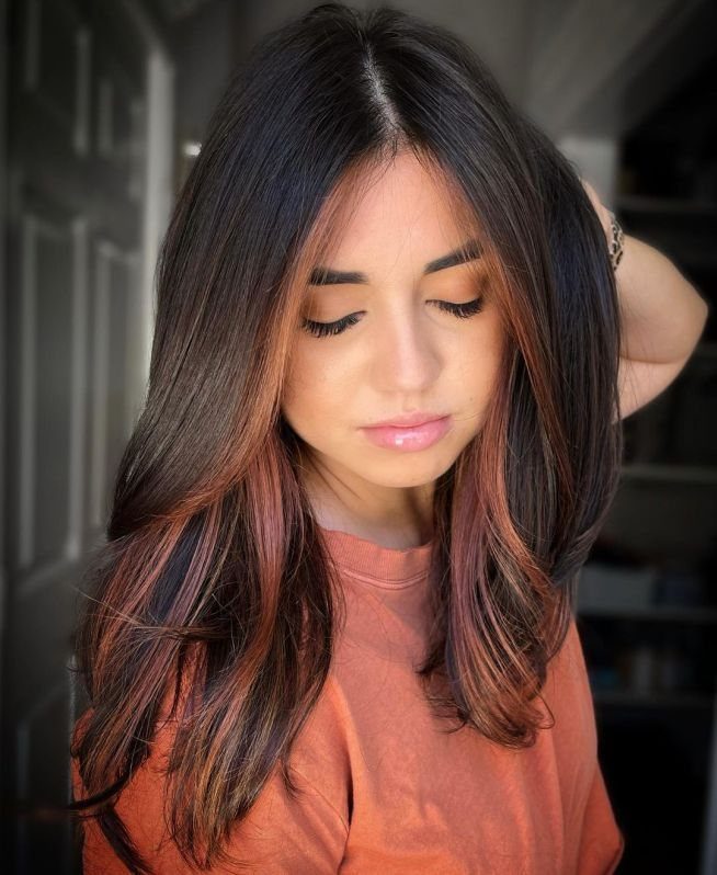Woman with long dark brown hair and copper-orange face-framing streaks
