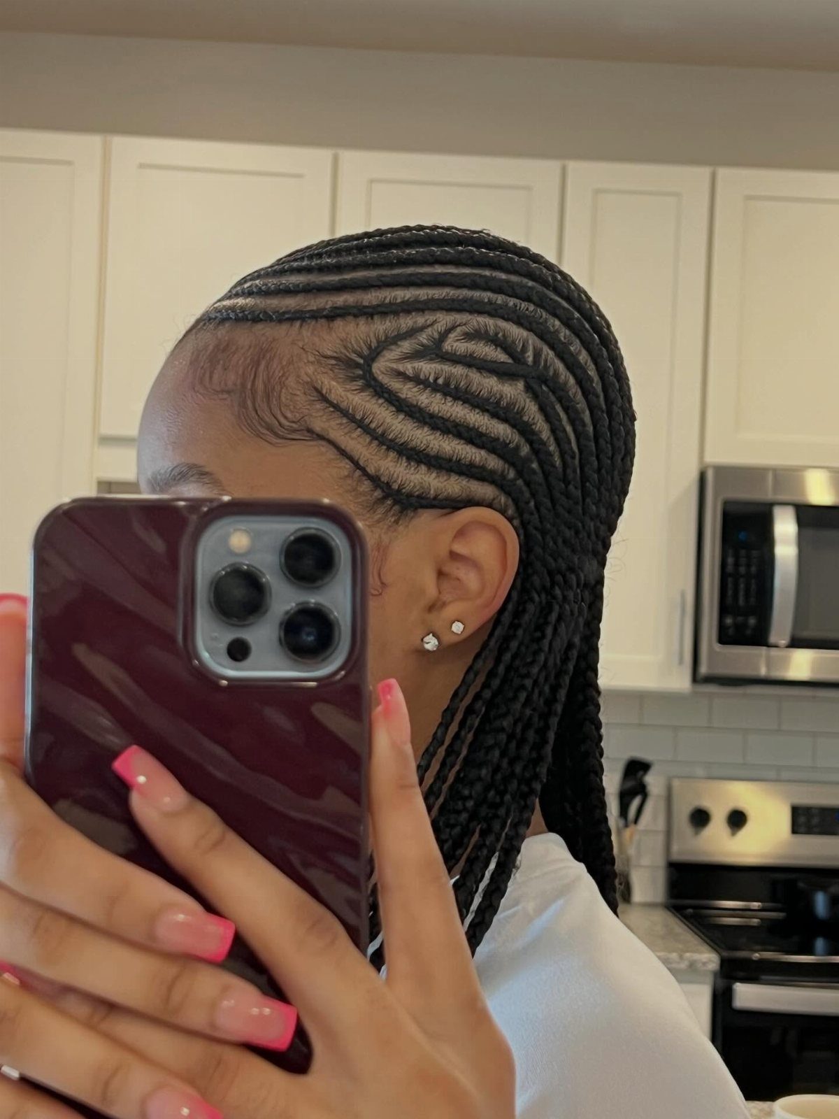 Black cornrow braids swept into a patterned side design and long braids