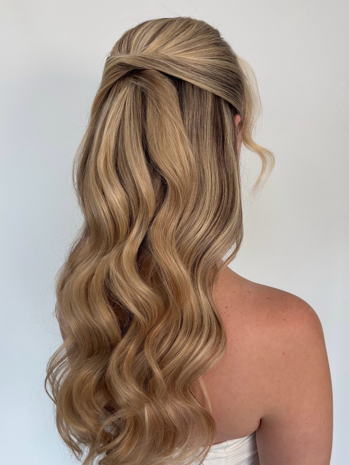 Blonde hair styled in a softly tousled half-updo with loose waves