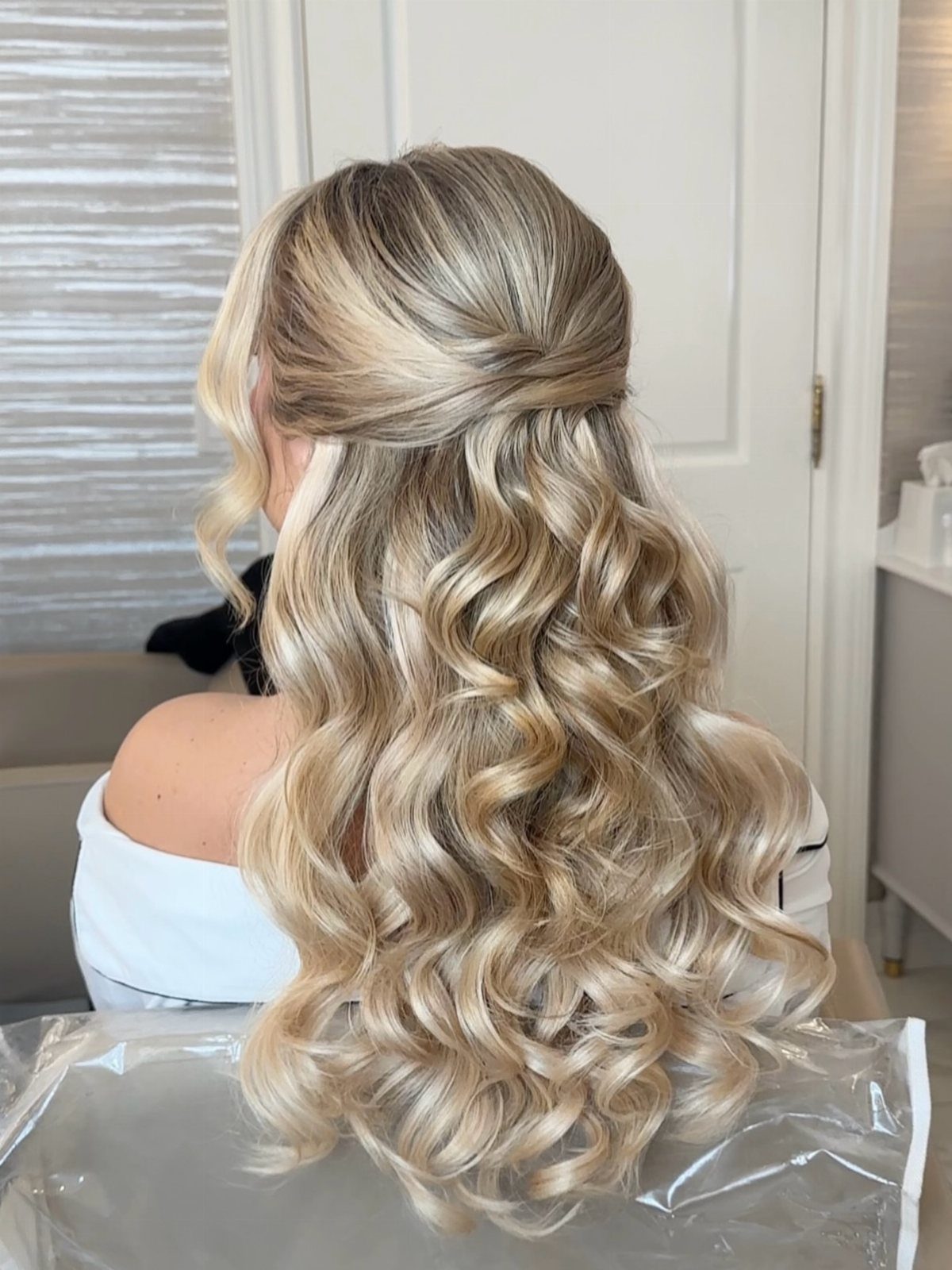 Blonde half up half down hairstyle with cascading curls viewed from behind