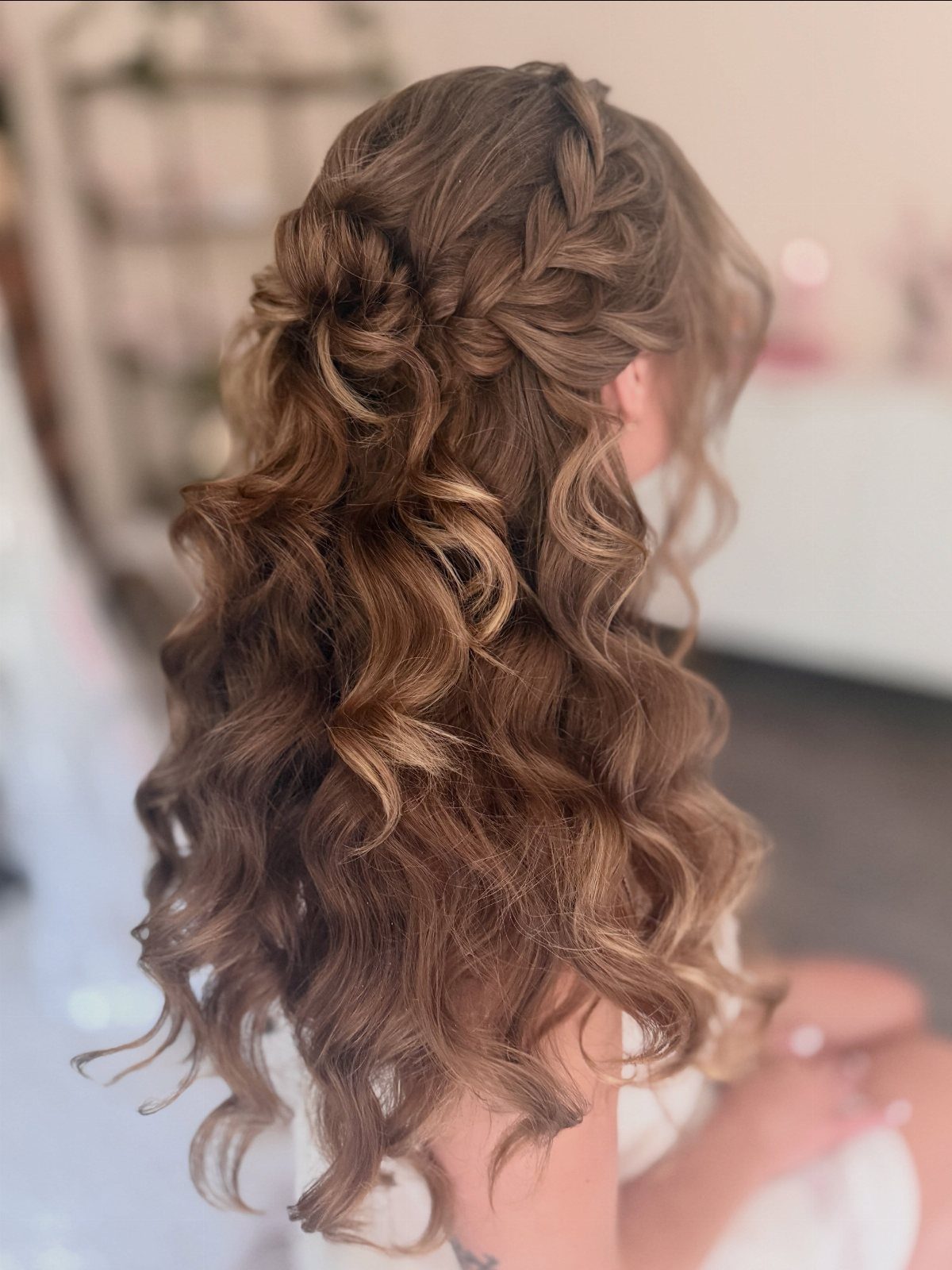 Braided half-up hairstyle gathered into a bun with long loose curls
