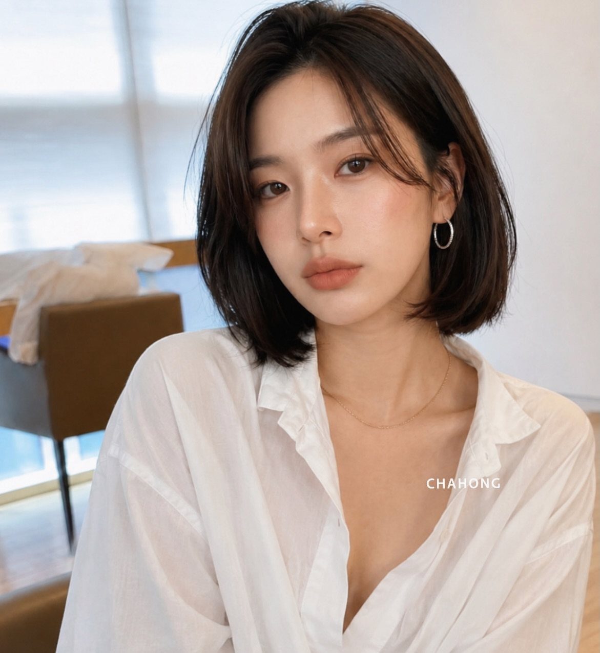 Woman with a polished chin-length dark bob and a white blouse