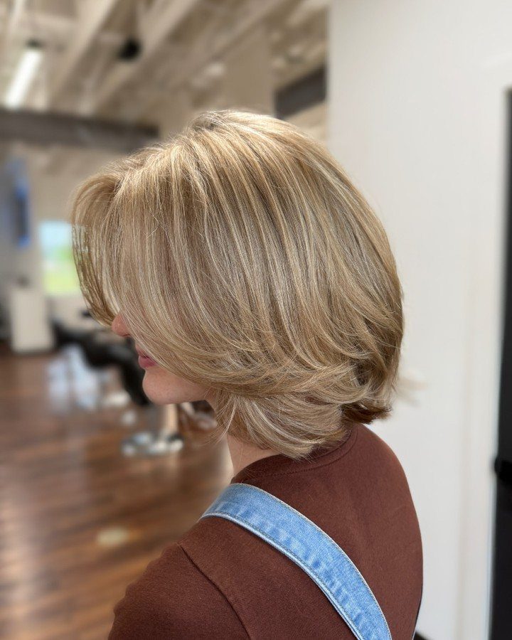 Layered blonde short haircut with feathered ends shown in salon profile