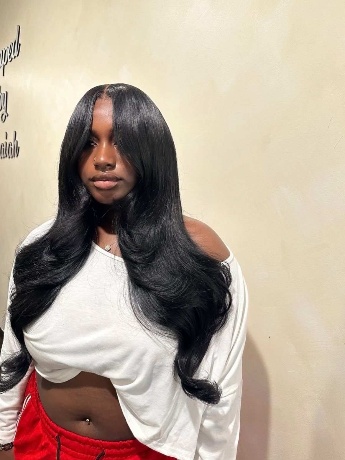 Woman with long, glossy black hair styled in a textured middle part and waves