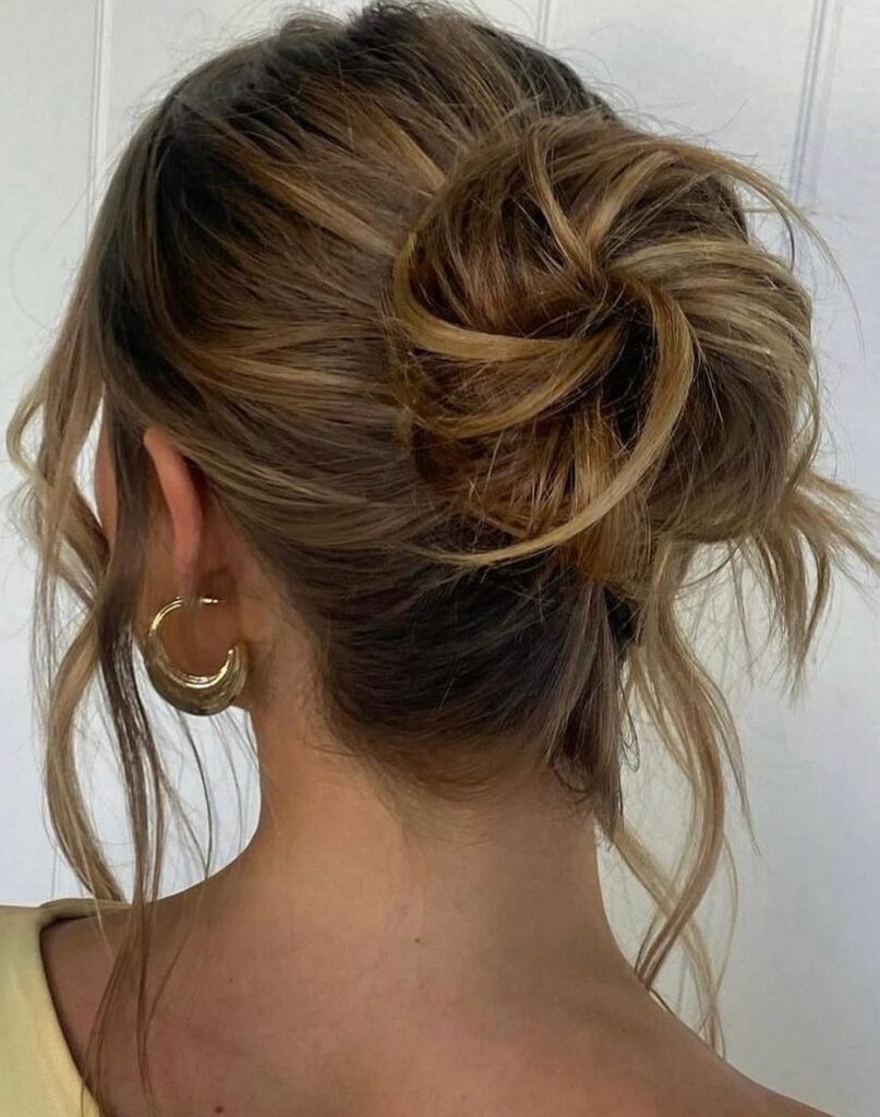 Loose brown messy bun with escaped strands viewed from behind